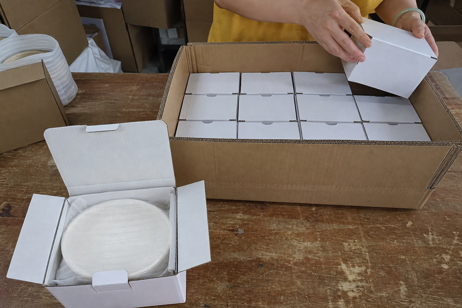 Foam-protected ceramic plate in a fitted inner box beside twelve boxes packed tightly in an export carton