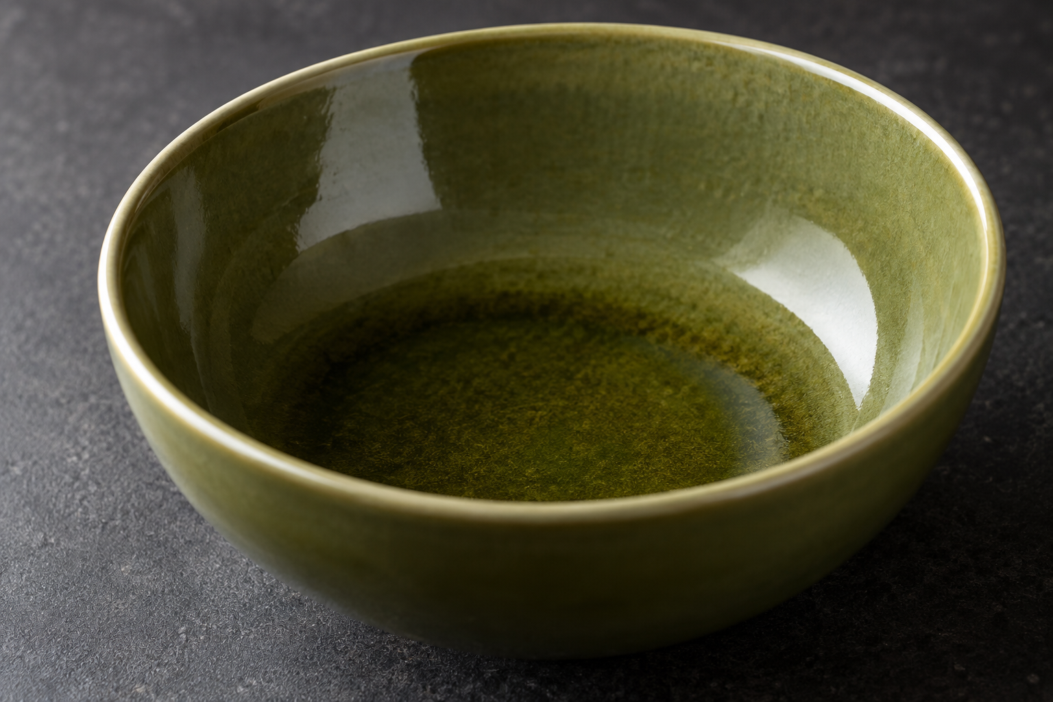 Close view of an olive ceramic bowl showing a lighter rim and deeper glaze color near the inner curve