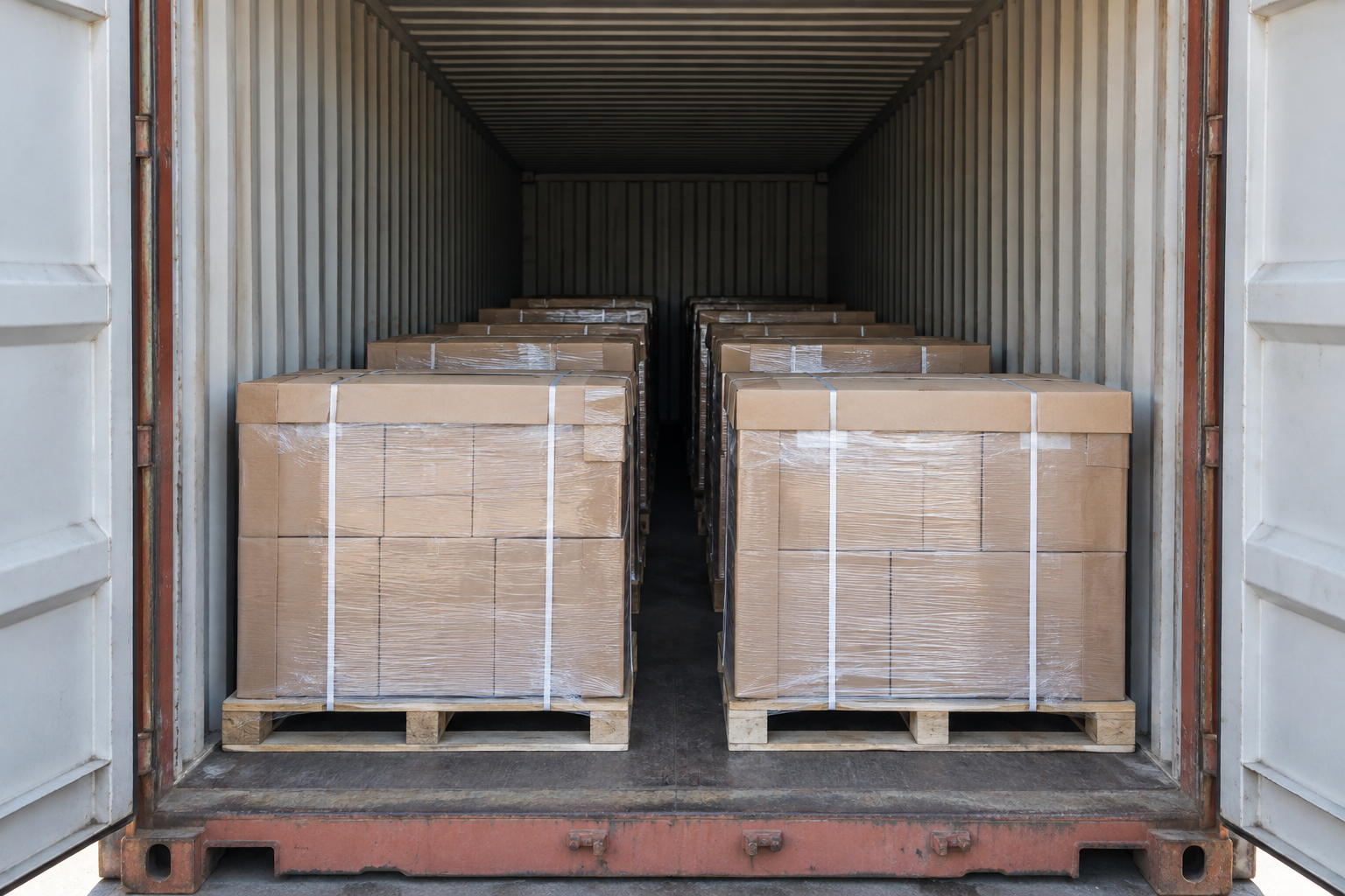 View into a shipping container with closely arranged palletized cartons and protective boards for a dinnerware load