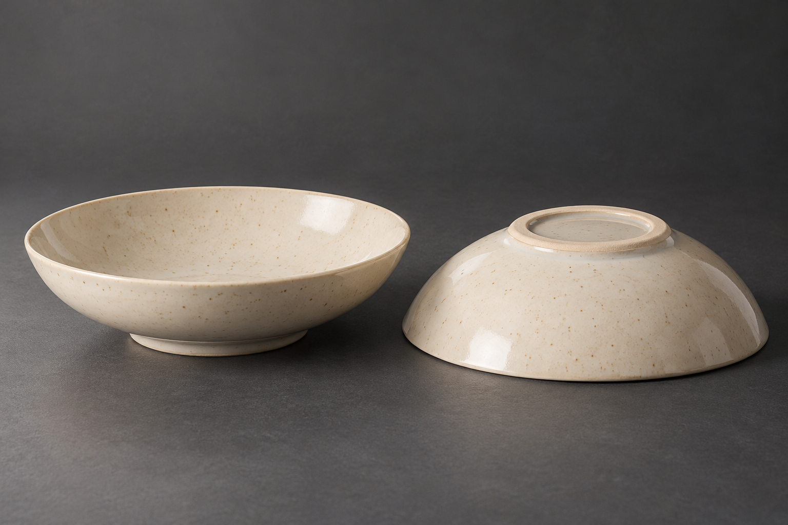 Upright and inverted ivory ceramic bowls showing the shallow side profile and unglazed foot ring on a gray surface